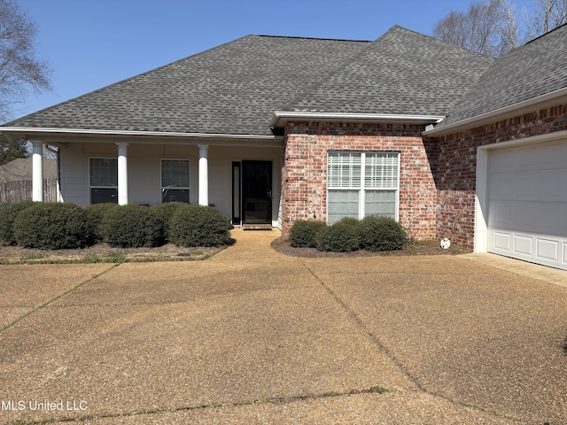 view of front of house with a garage, driveway, roof with shingles, and brick siding