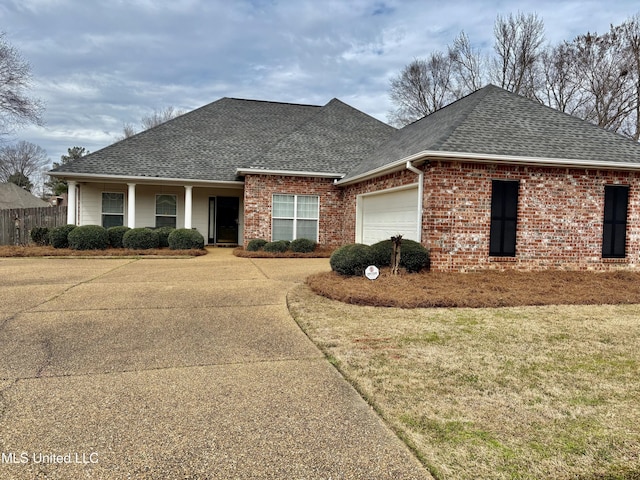 view of front of home featuring brick siding, a shingled roof, an attached garage, a front yard, and fence