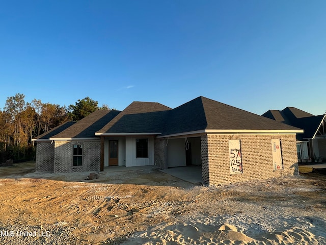 view of front of house with a shingled roof and brick siding