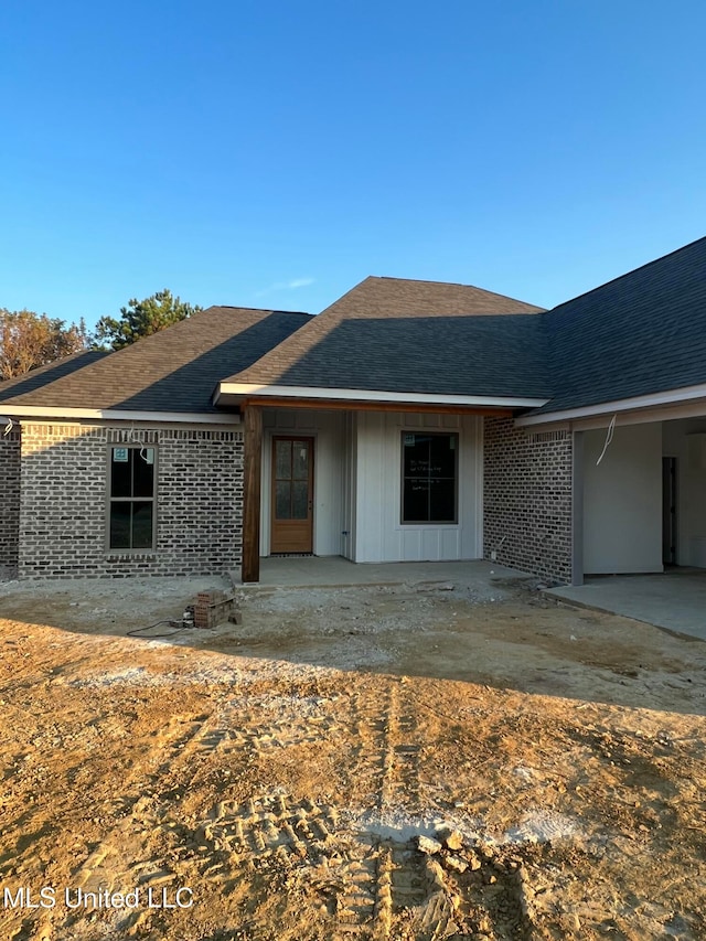 view of front of house with brick siding and roof with shingles