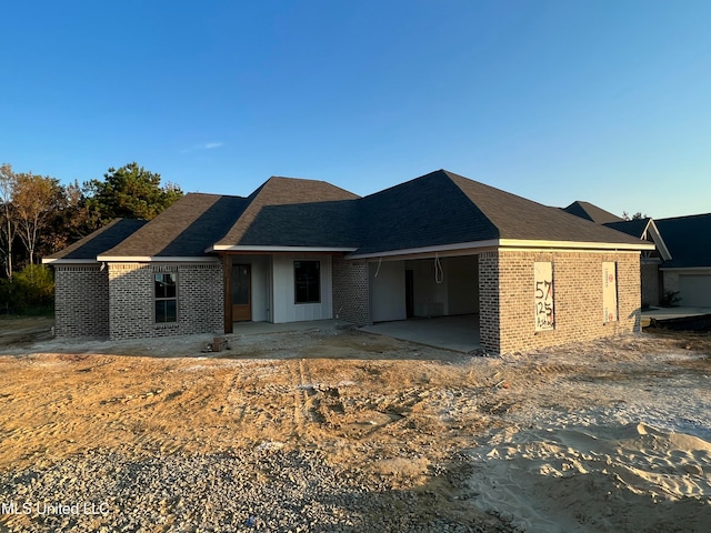 view of front of house featuring roof with shingles and brick siding