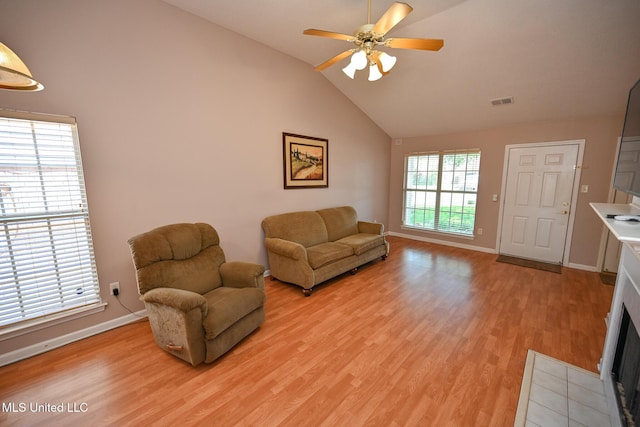 living area featuring light wood finished floors, a ceiling fan, baseboards, and lofted ceiling