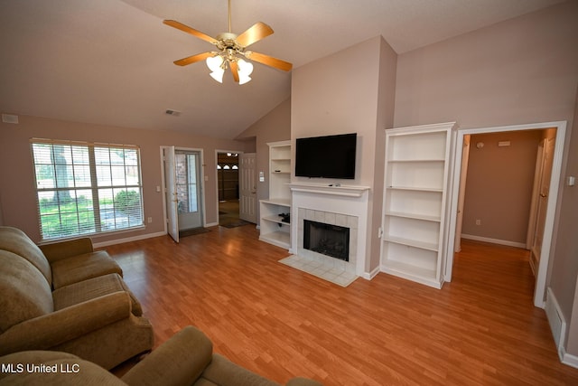 living room with high vaulted ceiling, light wood finished floors, a ceiling fan, baseboards, and a tile fireplace