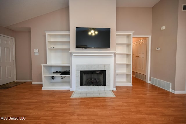 unfurnished living room with lofted ceiling, baseboards, visible vents, and wood finished floors