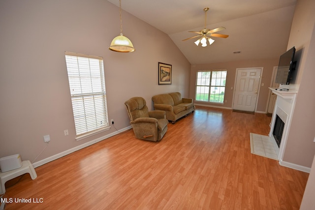 living area with baseboards, light wood-style flooring, a fireplace, and ceiling fan