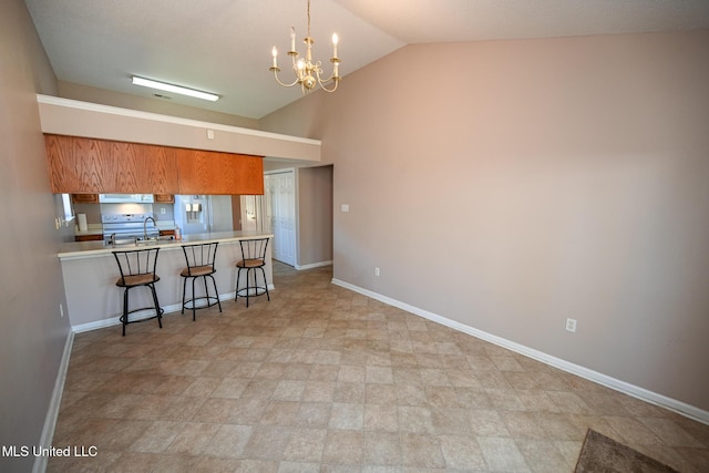 kitchen featuring lofted ceiling, baseboards, a breakfast bar, a chandelier, and extractor fan