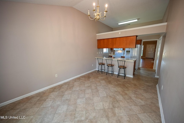 kitchen featuring a peninsula, brown cabinets, a notable chandelier, baseboards, and lofted ceiling