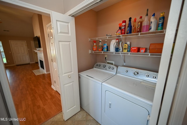 washroom with washer and dryer, laundry area, a fireplace with flush hearth, light wood-type flooring, and visible vents
