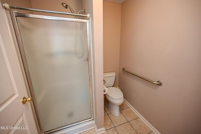 bathroom with a shower stall, tile patterned flooring, toilet, and baseboards