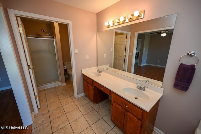 bathroom featuring toilet, tile patterned flooring, a shower stall, and a sink