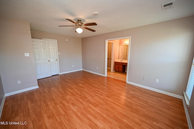 unfurnished bedroom featuring light wood-style flooring, a textured ceiling, baseboards, and visible vents