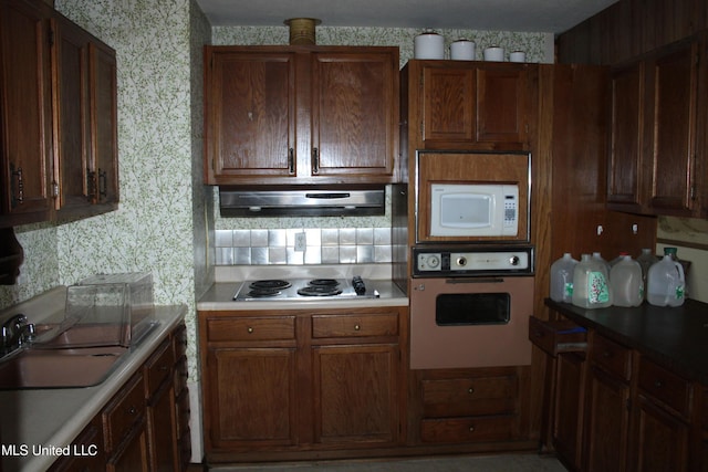 7000 Melrose Dr, Biloxi, MS 39532 - kitchen featuring wall oven, stainless steel electric stovetop, white microwave, wallpapered walls, and range hood