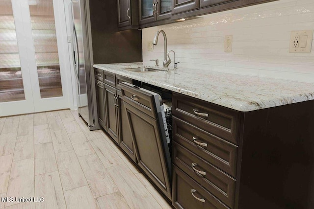 bar with a sink, backsplash, and light wood-style flooring