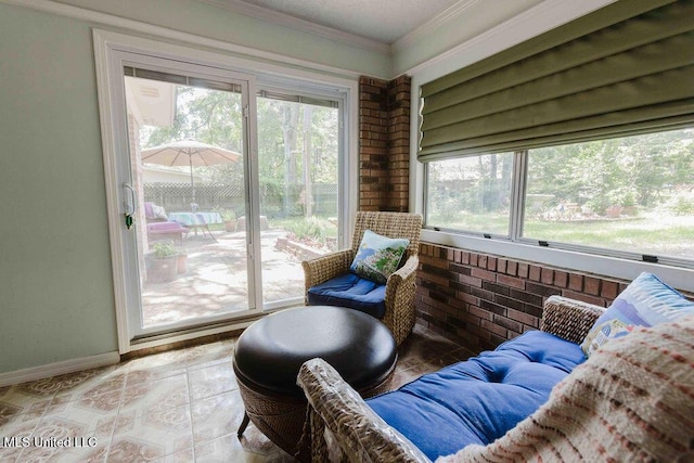 living area featuring baseboards, crown molding, and brick wall