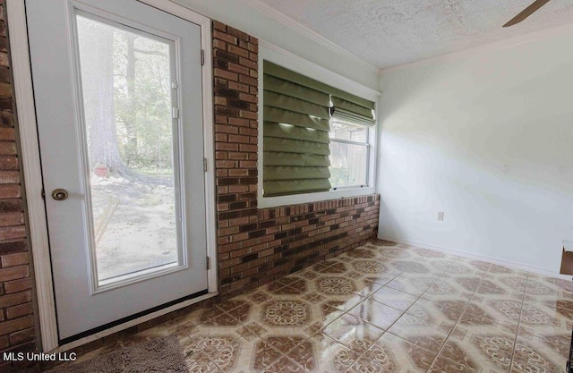interior space with a textured ceiling, ceiling fan, a healthy amount of sunlight, and brick wall