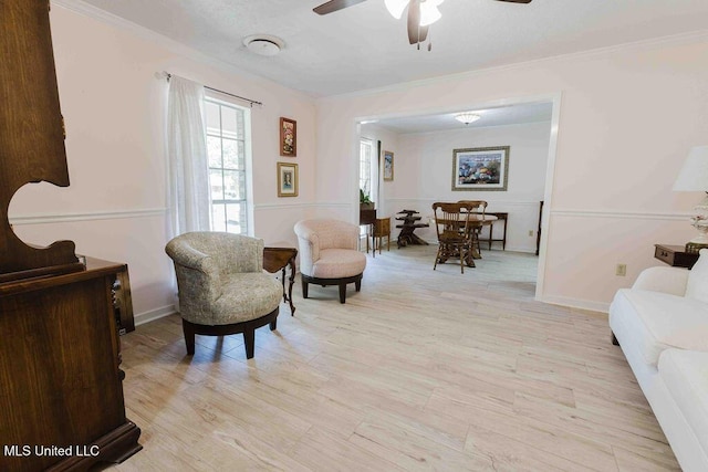living area featuring crown molding, light wood finished floors, and ceiling fan