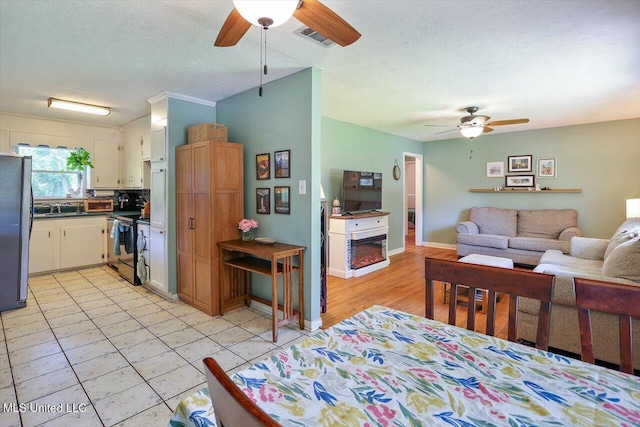 2709 Burma Dr, Pearl, MS 39208 - kitchen featuring ceiling fan, freestanding refrigerator, open floor plan, electric range oven, and a textured ceiling