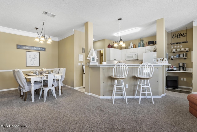 kitchen featuring white appliances, light carpet, kitchen peninsula, white cabinetry, and a breakfast bar area