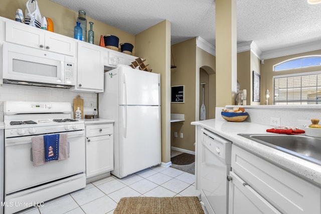 kitchen featuring decorative backsplash, white cabinets, and white appliances