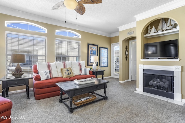 carpeted living room with built in shelves, ceiling fan, crown molding, and a textured ceiling