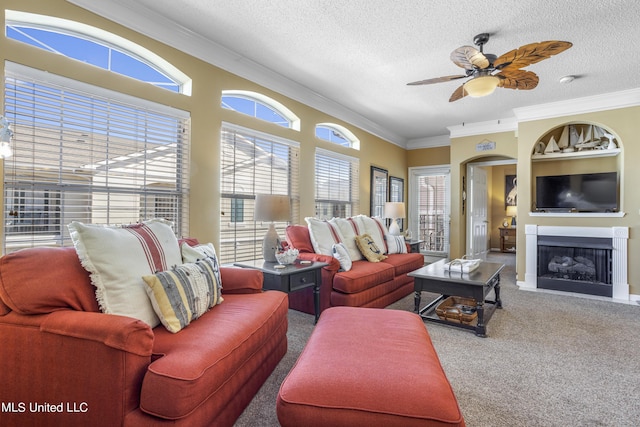 carpeted living room with built in shelves, a textured ceiling, ceiling fan, and crown molding