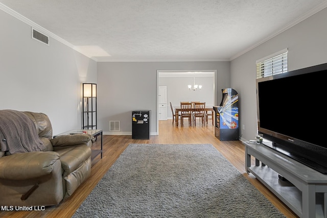 living room featuring crown molding, wood-type flooring, a textured ceiling, and a notable chandelier