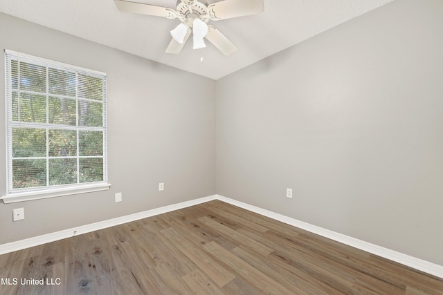 spare room featuring wood finished floors, baseboards, and ceiling fan