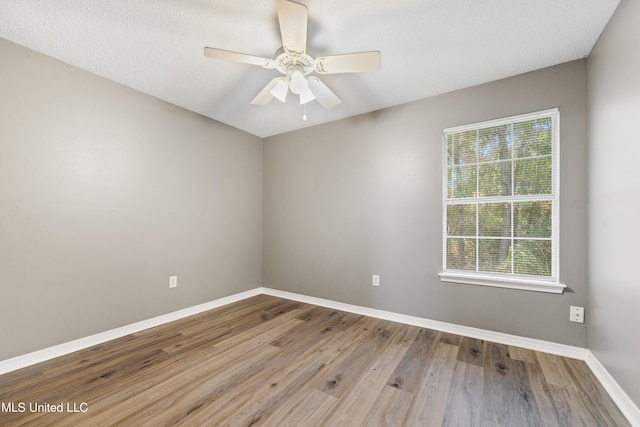 spare room featuring ceiling fan, baseboards, and wood finished floors