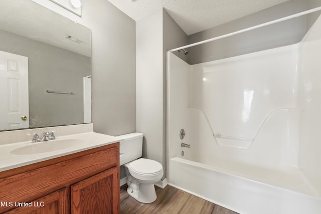 bathroom featuring visible vents, toilet, vanity, wood finished floors, and a textured ceiling