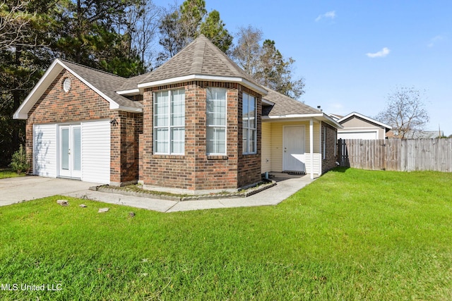 view of front of house with brick siding, roof with shingles, a front yard, and fence