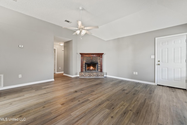 unfurnished living room with wood finished floors, a ceiling fan, visible vents, lofted ceiling, and a brick fireplace