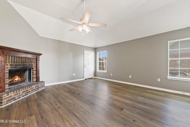 unfurnished living room featuring lofted ceiling, wood finished floors, a fireplace, and a healthy amount of sunlight