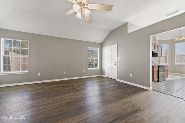 interior space featuring lofted ceiling, ceiling fan with notable chandelier, a textured ceiling, wood finished floors, and baseboards