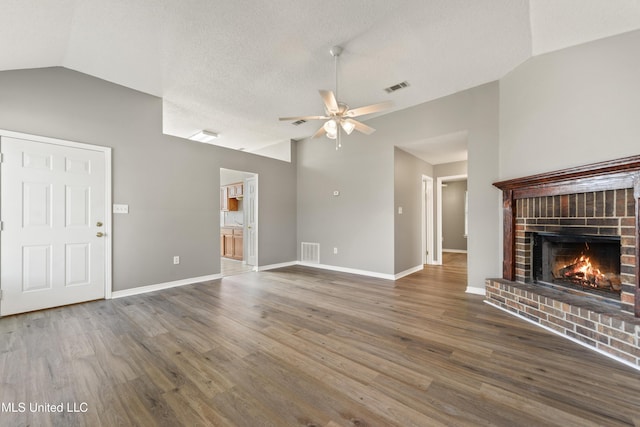 unfurnished living room featuring visible vents, a brick fireplace, and vaulted ceiling