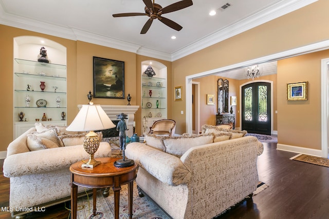 living room with ornamental molding, ceiling fan with notable chandelier, built in features, and dark hardwood / wood-style flooring