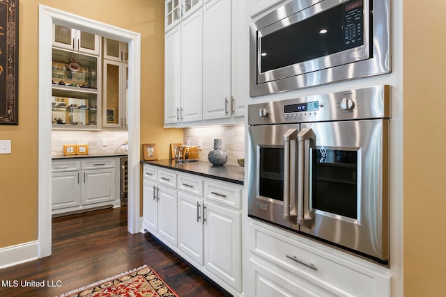 kitchen featuring white cabinetry, stainless steel appliances, decorative backsplash, and dark hardwood / wood-style floors