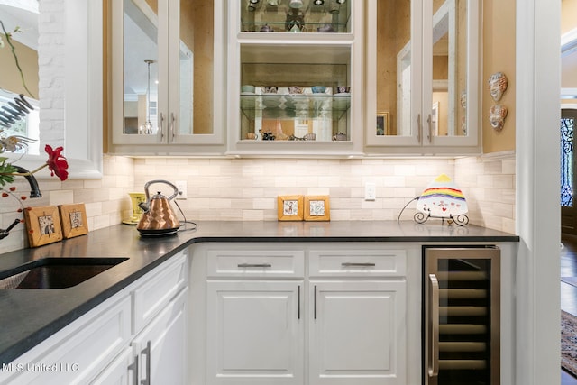 bar featuring sink, white cabinets, tasteful backsplash, and beverage cooler