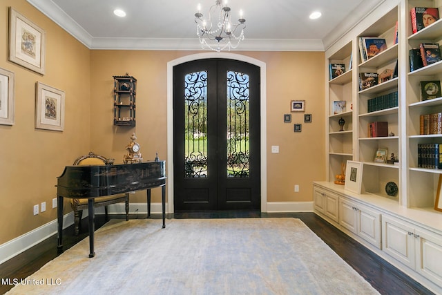 foyer entrance featuring french doors, dark hardwood / wood-style floors, a notable chandelier, and crown molding