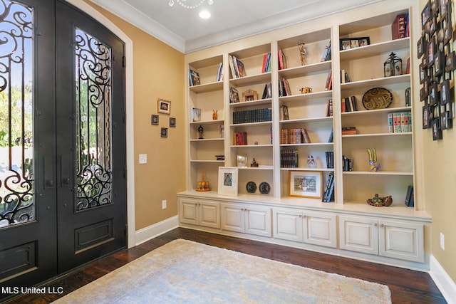 foyer with dark wood-type flooring, ornamental molding, and french doors