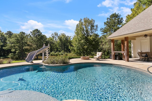 view of swimming pool with a water slide, a patio area, and ceiling fan