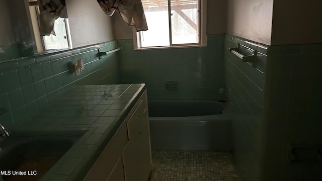 bathroom featuring tile walls, a bath, tile patterned flooring, and sink