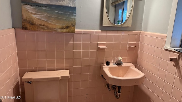 bathroom with toilet, sink, and tile walls