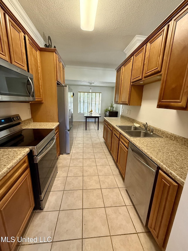 kitchen featuring appliances with stainless steel finishes, a sink, a textured ceiling, brown cabinetry, and light tile patterned floors