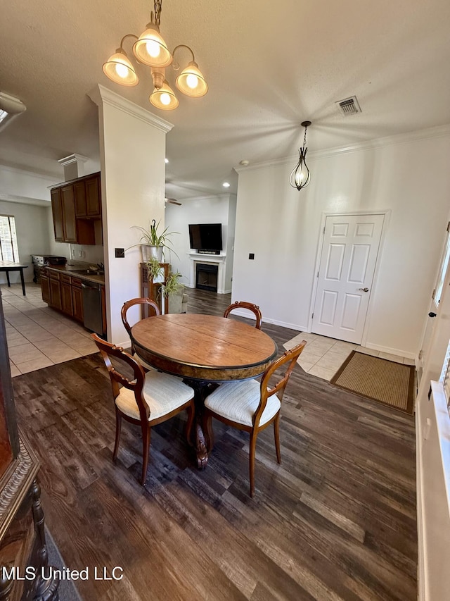 dining space with ceiling fan, visible vents, crown molding, a fireplace, and light wood-type flooring