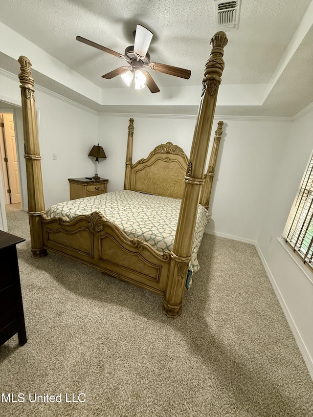 bedroom featuring light colored carpet, a textured ceiling, visible vents, and a raised ceiling