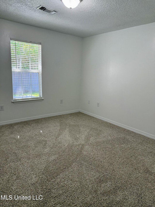 empty room featuring visible vents, a textured ceiling, carpet floors, and baseboards