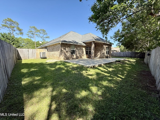 back of property with a lawn, brick siding, a fenced backyard, and a patio area