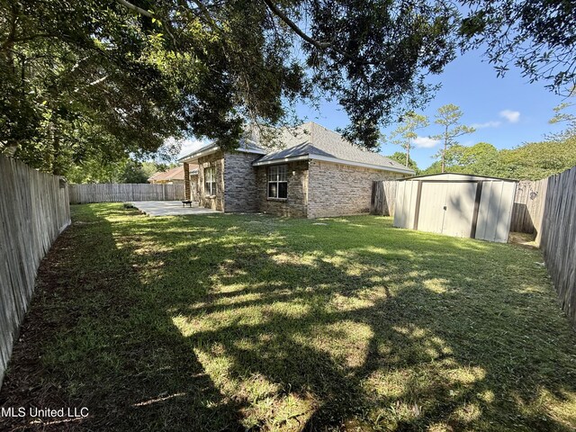 view of yard with a patio, an outbuilding, a fenced backyard, and a storage unit