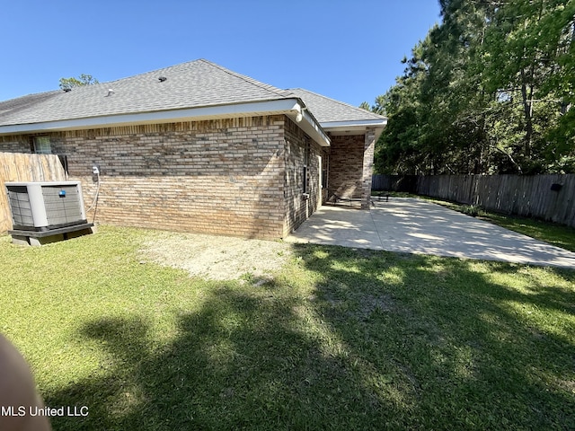 view of side of home with a lawn, a fenced backyard, a patio area, and brick siding