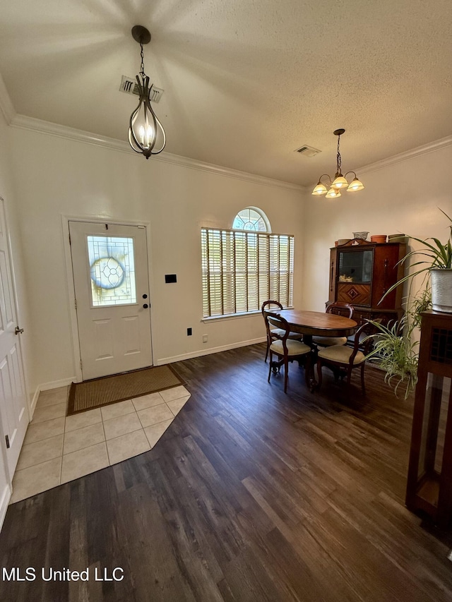 foyer with visible vents, ornamental molding, wood finished floors, and a notable chandelier
